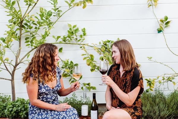 2 women sitting outside dinking a glass of wine